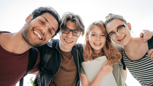 A diverse group of four teenage students happy and smiling together