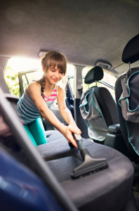 Teenager vacuuming car seats in the back of the car